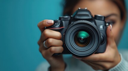 Beautiful young woman with a camera in her hands, professional at work ob blue background