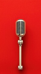 Fototapeta premium A vintage silver microphone stands upright against a vibrant red background perfect for podcasting music broadcasting or radio show announcements.