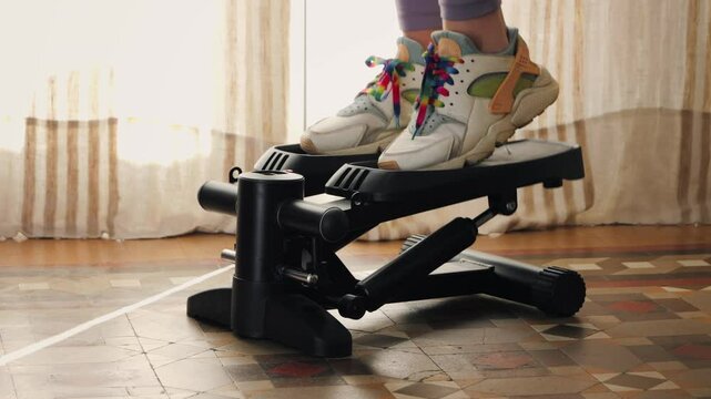 Legs with sneakers working out at home on stepper close up footage. High quality 4k footage