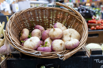 Fresh turnips in a woven basket at an outdoor market stall