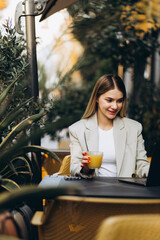 Young business woman sitting in a cafe drinking juice and working on a computer