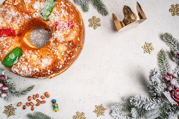 Roscon de reyes with cream and christmas ornaments on a white background, top view. Roscon is a...