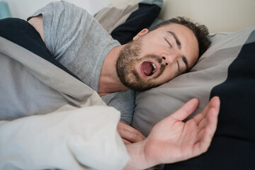 Man snoring loudly in his bed during night time