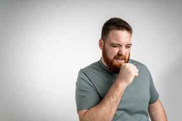 young red head bearded man feeling ill with a sore throat and flu symptoms, coughing with mouth...
