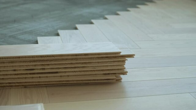 Worker installing wooden flooring with hammer and tapping block