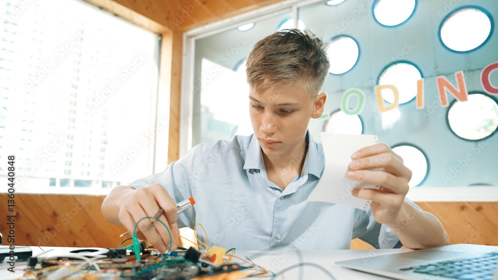 Poster smart boy inspect or learning to use electronic tool while looking at note. highschool student study