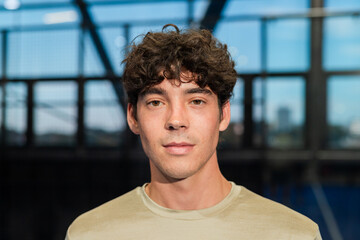 Young man standing confidently on padel tennis court, ready for match