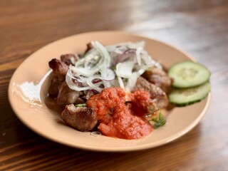 Savor the experience of Delicious Grilled Meat paired with Fresh Vegetables and flavorful Sauce. Enjoy grilled meat topped with crispy fried onions, rich tomato sauce, and crunchy cucumber slices