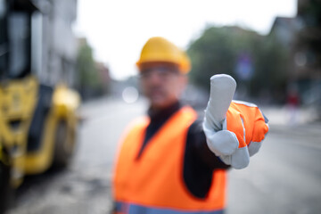 Construction worker signaling to stop or to direct on a job site during the day in an urban...