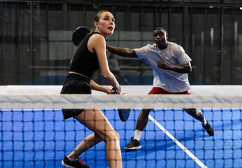Focused players engaged in intense padel tennis match on blue court
