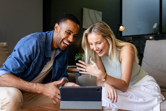 Celebrating engagement, diverse couple video chatting on tablet, smiling and waving