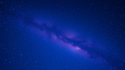 Fototapeta premium Cosmic galaxy swirling in purple hues against a starry night sky 