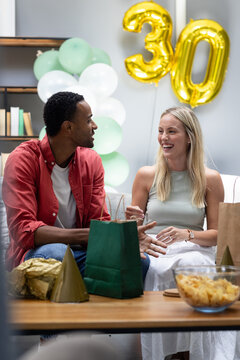 At party, Diverse friends celebrating 30th birthday with laughter and gifts at home