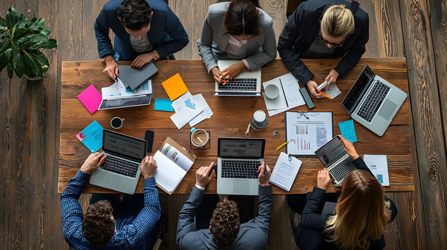 of professionals gathered around a table, discussing the implementation of innovative ideas for a business project, with digital devices in use 