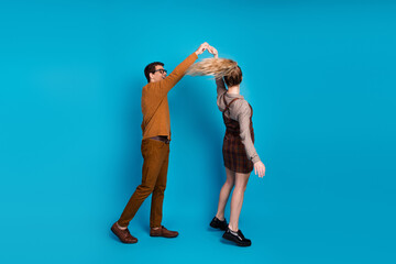 Young couple dancing joyfully against a vivid blue background, expressing vitality, happiness, and connection
