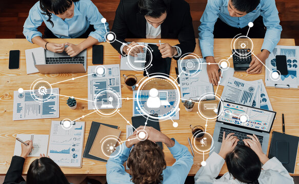 A diverse group of professionals engages in collaborative data analysis and strategy development, showcasing teamwork and technology in a modern office setting. Amity