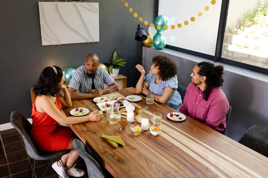 Diverse friends enjoying conversation and dessert at home during festive celebration