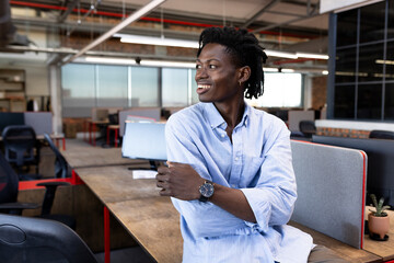 Smiling businessman in modern office looking away, feeling inspired and confident, copy space