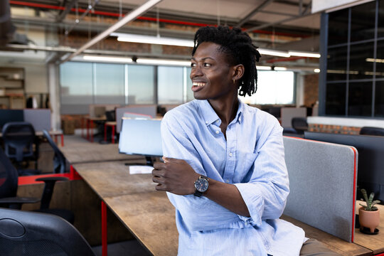 Smiling businessman in modern office looking away, feeling inspired and confident, copy space