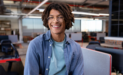 Smiling young man in modern office, enjoying creative work environment, copy space