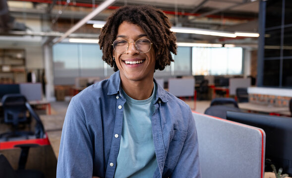 Smiling young man in modern office, enjoying creative work environment, copy space