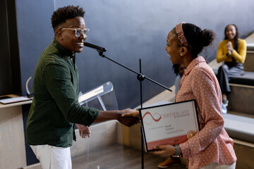At office, Smiling woman receiving certificate on stage during business award ceremony