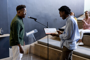 Man receiving award on stage while audience clapping in modern office setting
