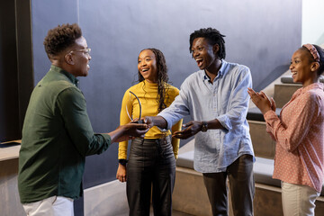 Celebrating success, diverse colleagues exchanging awards and sharing joyful moments at office