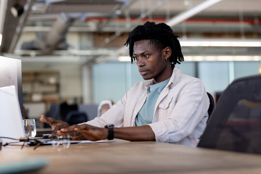 Working in modern office, professional focusing on computer tasks at desk
