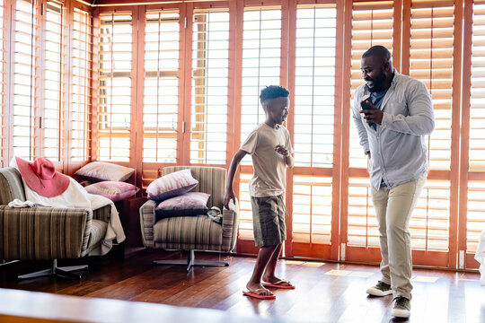 African American father and son dancing joyfully at home in living room