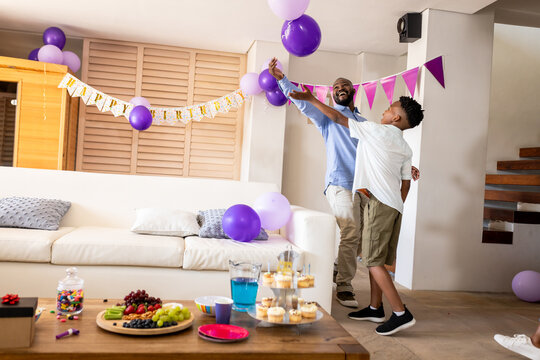 At party, Father and son decorating living room with balloons for birthday celebration, , copy space