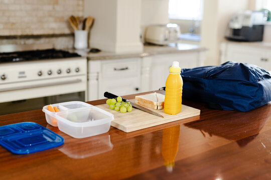 Preparing school lunch with sandwich, grapes, and juice bottle on kitchen counter