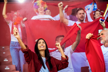 Sport fans lit torches in the stadium at the game. Red colors, flags, stadium.