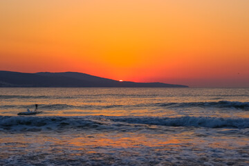 Fototapeta premium Enchanting sunrise over the sea. Red-orange sky and the first birds on the horizon