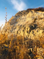 Colorful autumn hills reveal textured rock formations under a bright blue sky at golden hour