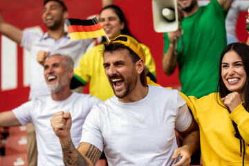 Fototapeta premium German football, soccer fans cheering at the stadium with flags and other equipment