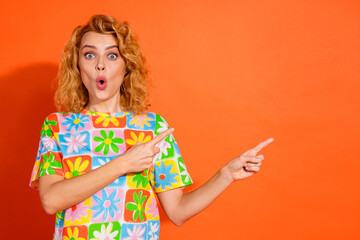 Young woman with a colorful floral shirt gesturing in surprise against an orange background