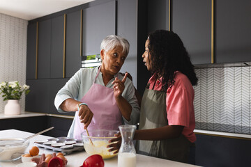 Senior mother and adult daughter baking in modern kitchen, sharing recipes, at home