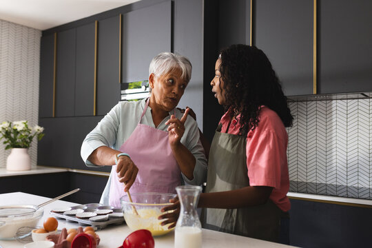 Senior mother and adult daughter baking in modern kitchen, sharing recipes, at home
