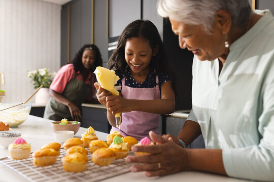 Decorating cupcakes in kitchen, happy grandmother and child sharing joyful moment , at home