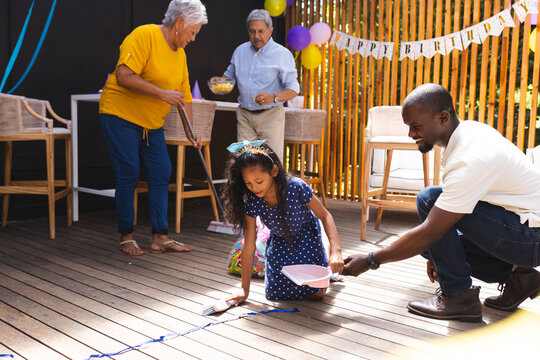 At party, happy family cleaning up after birthday party on patio, enjoying time together