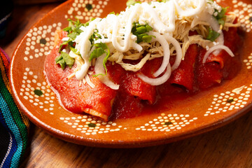 Entomatadas. Also known as Enjitomatadas, a typical dish of Mexican cuisine prepared with corn tortilla, tomato sauce and stuffed with shredded chicken meat. Classic homemade recipe.