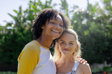 Smiling female friends enjoying sunny day together at backyard poolside