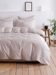 Double bed with fluffy duvet in a beige duvet cover and four pillows close-up front view vertical photo