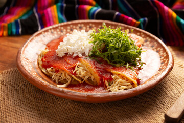 Entomatadas. Also known as Enjitomatadas, a typical dish of Mexican cuisine prepared with corn tortilla, tomato sauce and stuffed with shredded chicken meat. Classic homemade recipe.