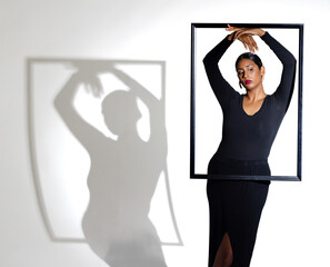 Elegant woman posing with frame, creating artistic shadow on wall