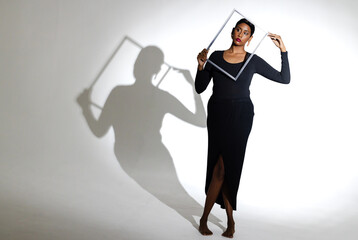 Confident woman in black dress posing with picture frame in studio
