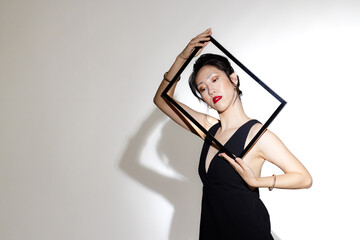 Elegant asian woman posing with geometric frame, showcasing modern fashion style, copy space