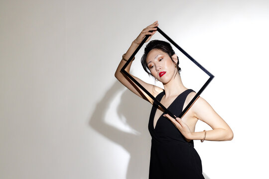 Elegant asian woman posing with geometric frame, showcasing modern fashion style, copy space