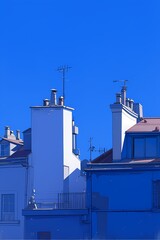 Rooftop View with Chimneys and Antennas Against Clear Blue Sky